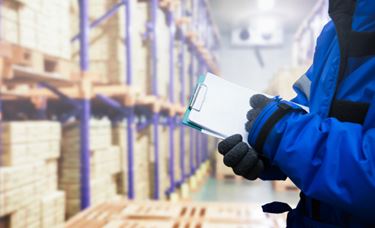 Hand of quality control worker checking goods on delivery in the cold room warehouse